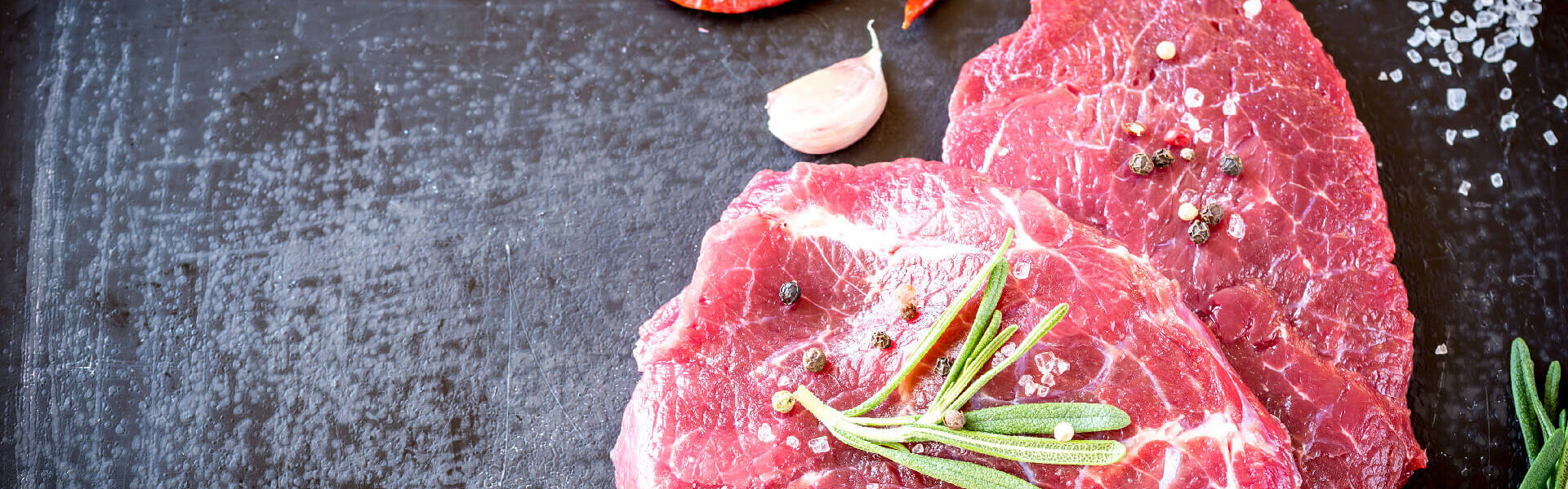 Zwei rohe Filetstücken mit Gewürzen und Kräutern auf Schieferplatte