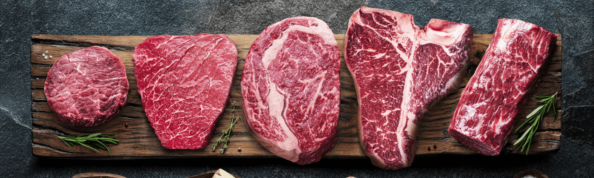 Eine Auswahl an hochwertigen Fleischedelstücken auf einem Holzbrett