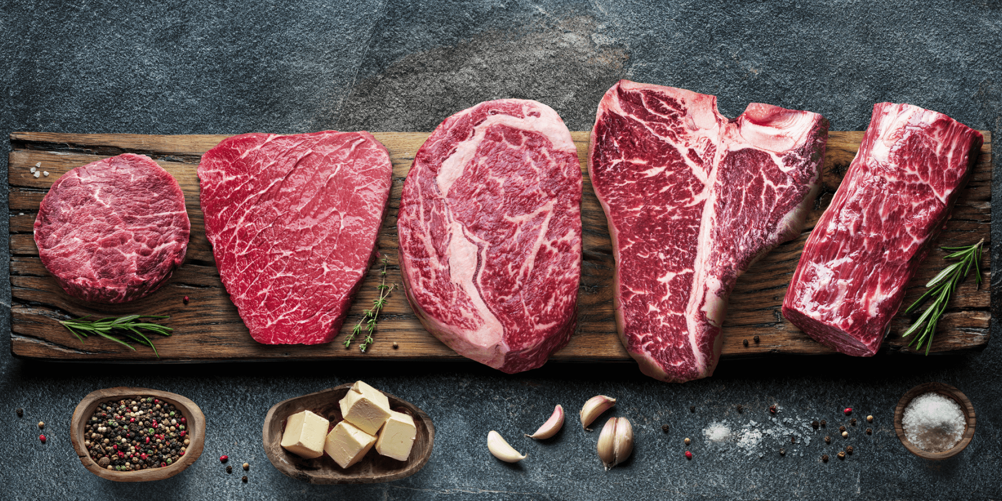 Eine Auswahl an hochwertigen Fleischedelstücken auf einem Holzbrett