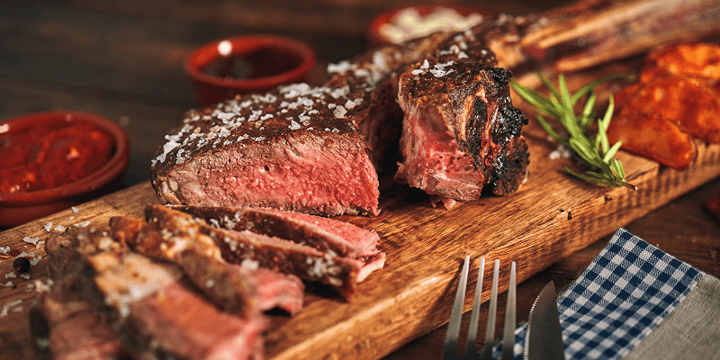 Ein angeschnittenes Fleischstück appetitlich serviert auf einem Holzbrett