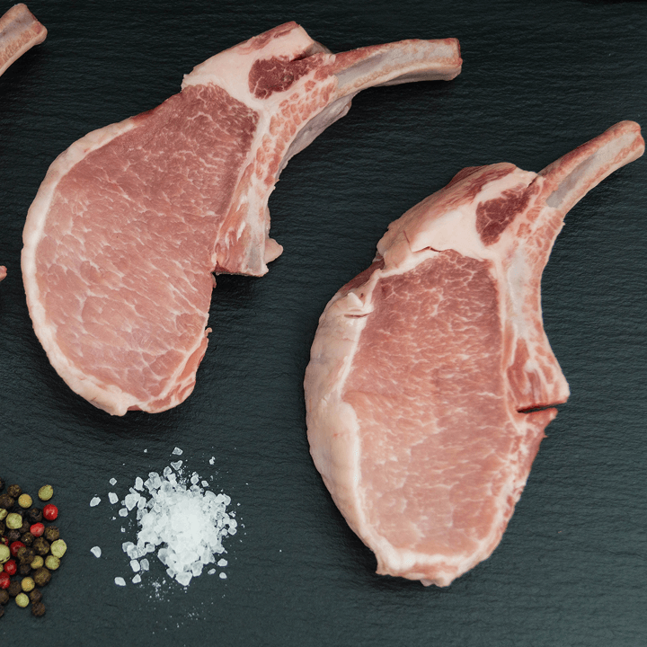 Zwei Fleischstücke vom Schwein auf Schieferplatte