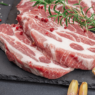 Zwei rohe Fleischstücke mit Rosmarin auf einer Schieferplatte