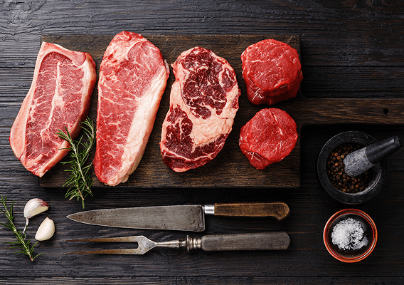 Eine Auswahl an hochwertigen Fleischedelstücken auf einem Holzbrett