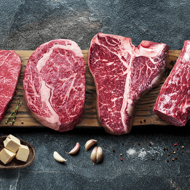 Eine Auswahl an hochwertigen Fleischedelstücken auf einem Holzbrett